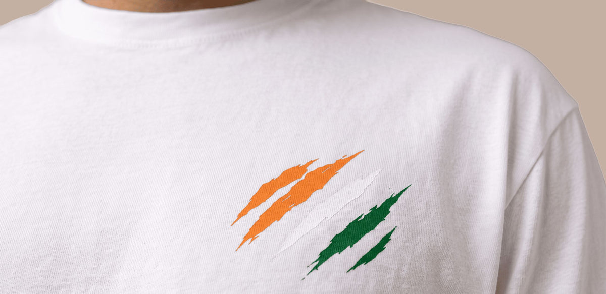 A close-up of a white crewneck t-shirt featuring a graphic of three orange and green paint strokes on the chest, resembling a stylized scratch or flag design.